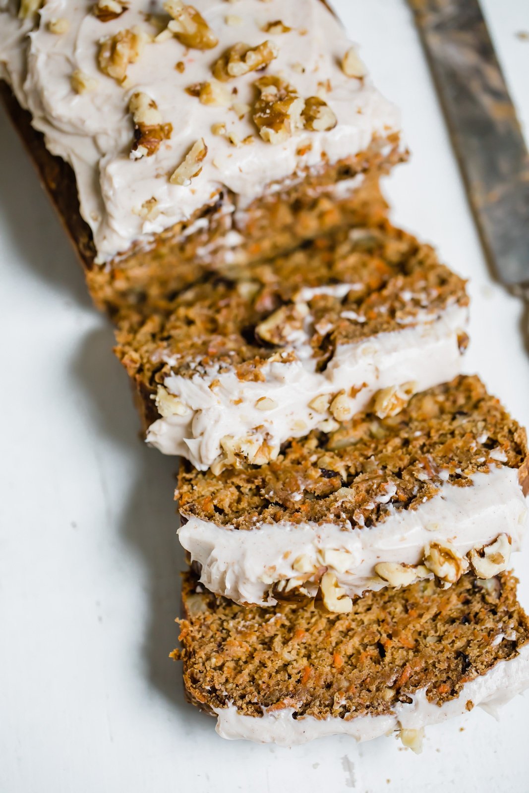carrot cake banana bread with cream cheese frosting and walnuts on top