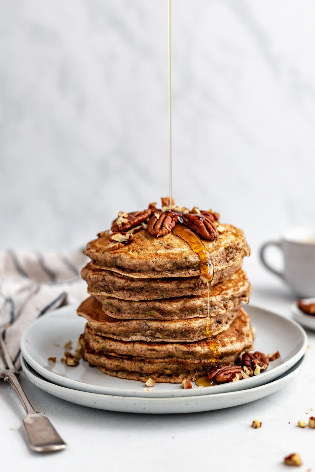 drizzling syrup on a stack of healthy zucchini pancakes